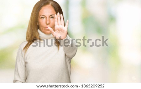 Beautiful middle age adult woman wearing winter sweater over isolated background doing stop sing with palm of the hand. Warning expression with negative and serious gesture on the face.
