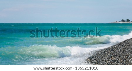 Blue sea and waves on a pebble beach. Seascape with waves and clear sky.