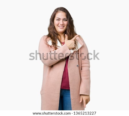 Beautiful plus size young woman wearing winter coat over isolated background cheerful with a smile of face pointing with hand and finger up to the side with happy and natural expression on face