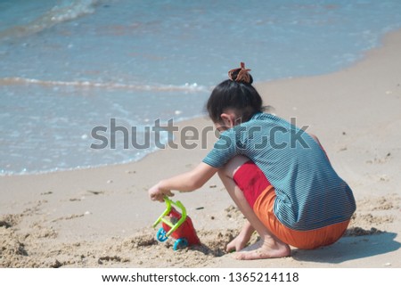 Girl playing the sand on beach, travel holiday at sea, back view with no face