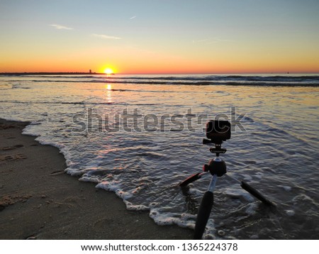 A action camera on tripod with wave on the sand beach during sunset in The Hague