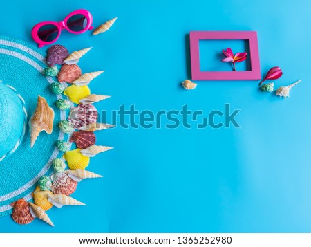 Summer  holiday  concept  setting  with  straw  hat,colorful  seashells,sunglasses  and  wooden  picture  frame  on  blue  background