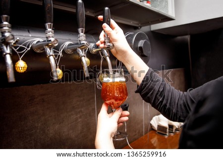 Bartender pours fresh ale from tap in tap.