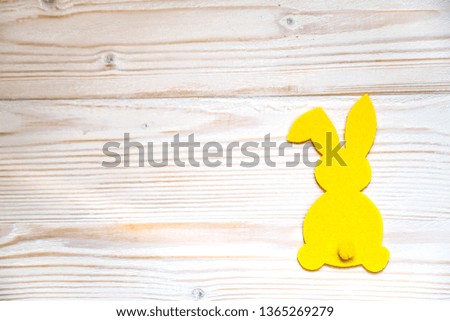 Silhouette of a yellow Easter bunny on a white wooden background.