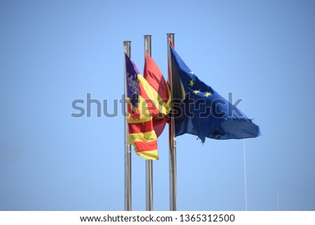 Three flags in the wind: the Balearic flag, the Spanish flag and the European Union (EU) flag on the Balearic island of Mallorca, Spain
