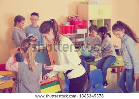 Smiling schoolgirls drawing a chalkboard, children at lesson in class