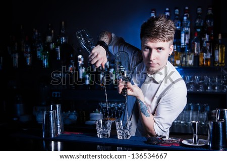 Bartender bartender is pouring a drink and looking at the camera Royalty-Free Stock Photo #136534667
