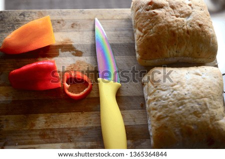 Artisan bread, rolls and red peppers. Fresh bread orange and red peppers on cutting board. Moody lighting, artisan cooking. Peppers on wooden cutting board, next to baked bread.