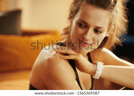 pensive healthy sports woman in sport clothes listening to the music with headphones in the modern living room.