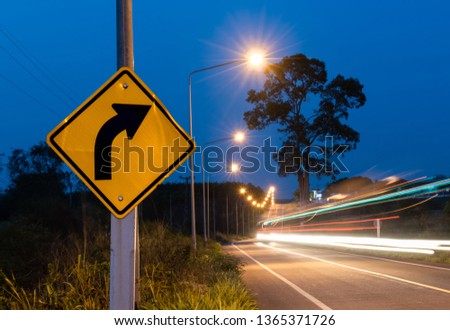 Turn right street sign with car ligh line motion in twilight sky time.
