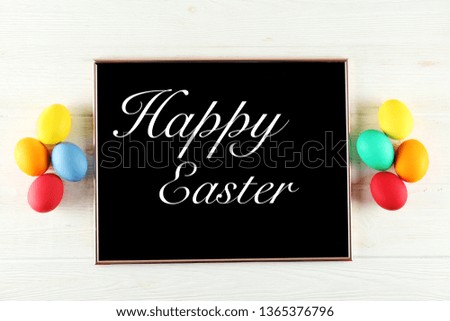 Blackboard with Happy Easter text, different colorful boiled paintd eggs. Greeting card concept with traditional holiday attributes. Wooden background, close up, top view, copy space, flat lay.