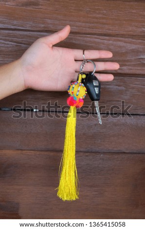 hand holding car keys, isolated on brown background, inside clipping path 