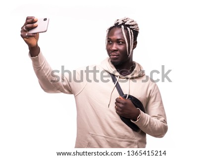 Close up of young beautiful dark-skinned man with afro hairstyle in casual smiling with teeth, holding smartphone, making selfie photo isolated on white background