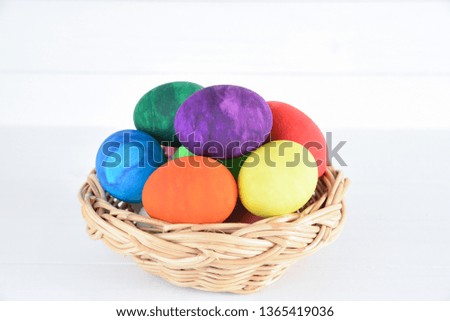 Colorful handmade easter eggs in a basket on white wooden background. Happy Easter Day, Easter eggs concept.