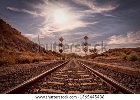 A railway line leads from the middle of the picture directly to the horizon with the sun as backlight