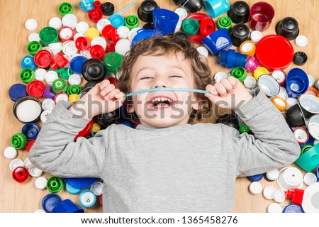 Conceptual photography about the use of plastics. Child lying on the floor surrounded by plastic stoppers.