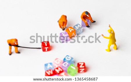 Miniature people. The concept of a collective solution to any problem. Miniature toy workers build the letter "TEAM". Close-up view.