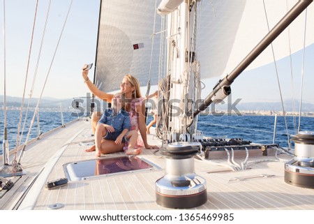 Mother and son child on sailing yacht together on summer vacation, luxury exclusive day out adventure outdoors. Smiling, taking selfies with smartphone, leisure recreation fun travel family lifestyle.