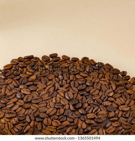 Close-up coffee beans at the bottom of the picture on a matte beige surface