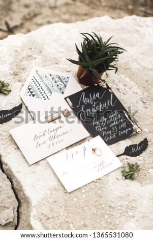 Wedding Invitation Cards Papers in rustic, boho style, Laying on the sand, Decorate With Leaves, succulents. Wedding invitation cards, craft envelopes. Overhead view. Flat lay, top view