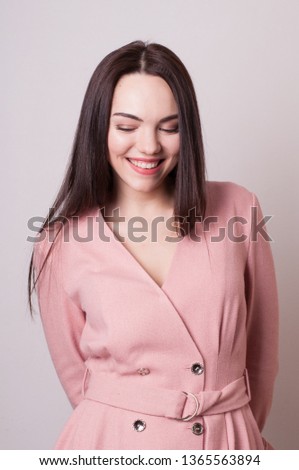 Portrait of young beautiful woman in elegant pink dress with dark long hair on light background