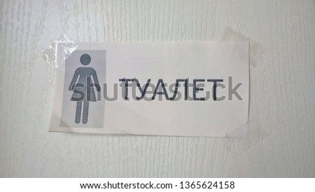 Texture, background, wallpaper, image of a white wooden door with the inscription "Toilet" pasted on the adhesive tape in Russian and an adjacent picture denoting a woman.