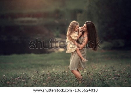 Beautiful mother and daughter are walking in the park, hugging and having fun. Image with selective focus and toning.