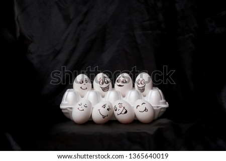  Real hand-painted eggs.  White eggs with faces drawn arranged in carton.Graffiti eggs in an egg box. Copy space. Black background. 