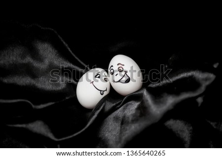 Real hand-painted eggs.  White eggs with faces drawn arranged in carton.Graffiti eggs in an egg box. Copy space. Black background. 