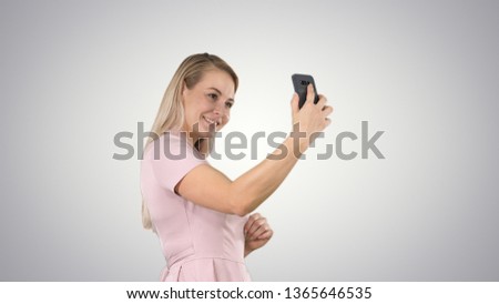 Beautiful young woman doing selfies on gradient background.