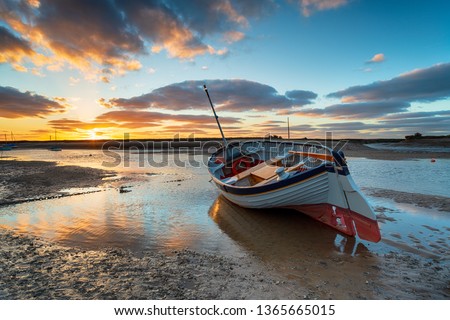 Stunning sunset over a fishing boat at Burnham Overy Staithe on the Norfolk Coast Royalty-Free Stock Photo #1365665015