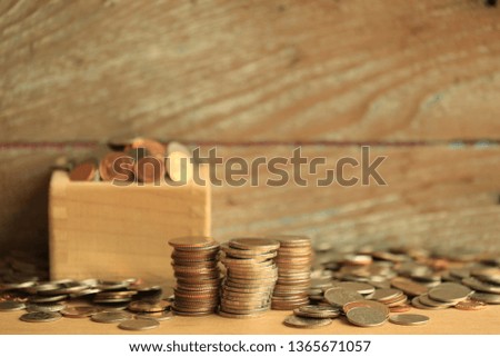 Many Thai coins are stacked on the floor. Wooden boxes with coins and old wooden floors as background selective focus and shallow depth of field