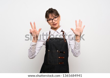 Young woman with apron counting eight with fingers