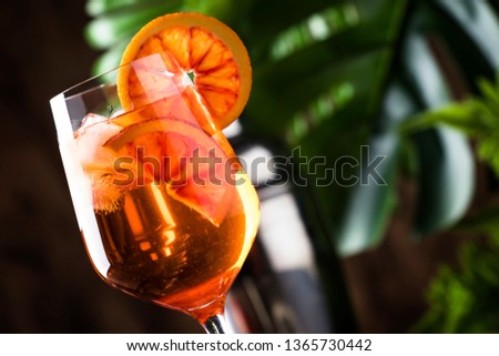 Aperol spritz cocktail in big wine glass with orange slices, summer cool fresh alcoholic cold beverage. Wooden bar counter background with tools, summer mood concept 