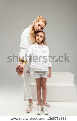 Pictures on the wrists. Long-haired peaceful woman having connection with little girl while presenting lock and key on the wrists