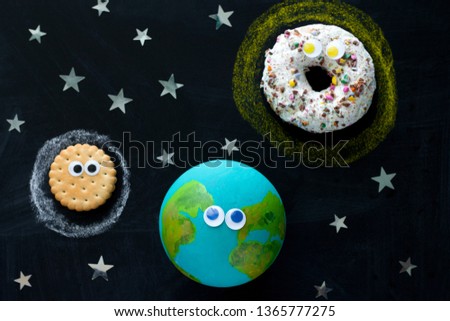 cute model of the Earth, Sun and Moon with googly eyes on the chalkboard, a donut, a globe and a cookie on the chalkboard