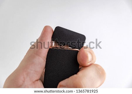 electronic lighter in man's hand, matte surface, gold frame, short focus, on a white background