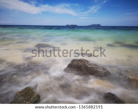 The beautiful silky smooth water waves and rocks on the sea shore.