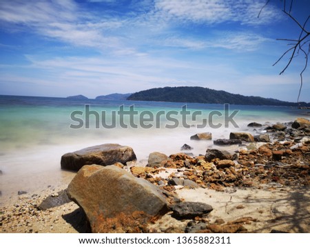 The beautiful silky smooth water waves and rocks on the sea shore.