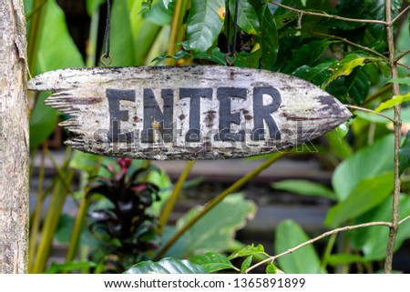 Text enter on a wooden board in a rainforest jungle of tropical Bali island, Indonesia. Enter wooden sign inscription in the asian tropics. Close up