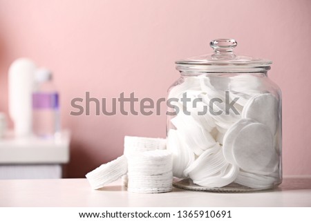 Glass jar with cotton pads on table in bathroom, space for text Royalty-Free Stock Photo #1365910691