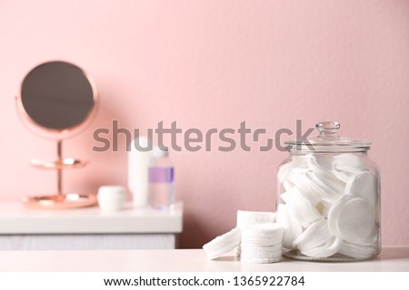 Glass jar with cotton pads on table in bathroom, space for text Royalty-Free Stock Photo #1365922784