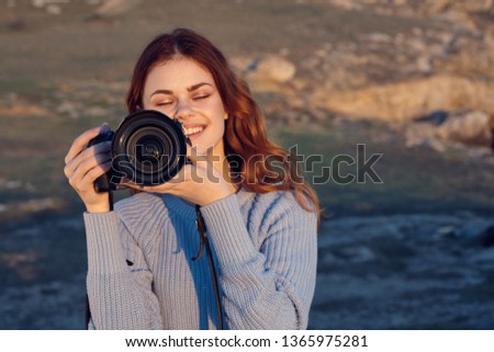 Cheerful pretty woman photographer with a camera in her hands on nature
