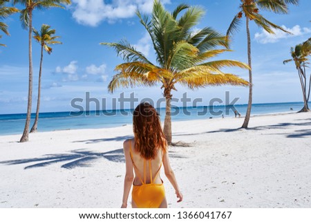 A woman in a yellow swimsuit walks on the beach Caribbean islands Exotic paradise