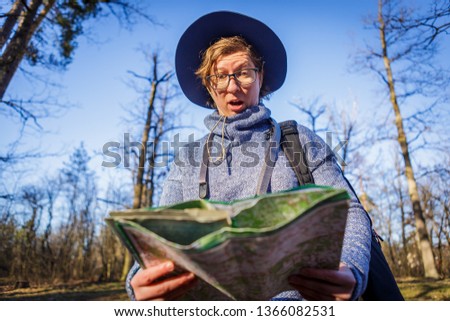 female tourist in the forest looks at a map