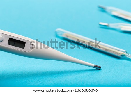 mercury and electrick thermometers on blue  background close up view- Image
