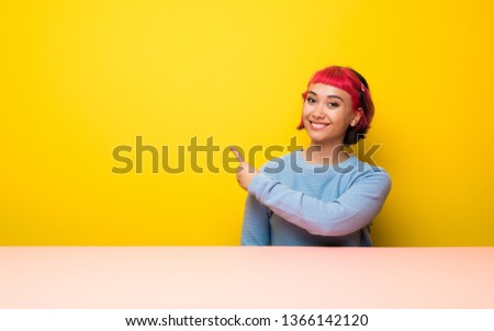 Young woman with pink hair pointing back