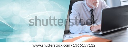 Mature businessman using a laptop in office. panoramic banner