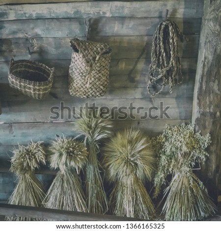 sheaves of wheat, old baskets and ropes on the wooden wall. Vintage with retro film filter effect