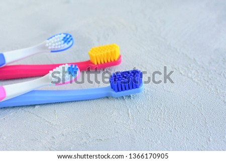 Colorful family toothbrushes with selective focus on grey cement background. Dental concept with male, female and kids toothbrush on neutral backdrop. New toothbrushes for cleaning teeth.